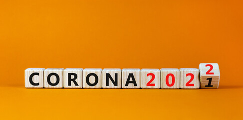 Symbol of covid-19 pandemic in 2022. Turned a wooden cube and changed words 'corona 2021' to 'corona 2022'. Beautiful orange background, copy space. Medical, covid-19 pandemic in 2022 concept.