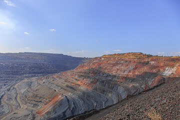 The horizons of a large iron ore quarry on a sunny day. The process of open-pit mining in a quarry.