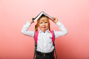 Book roof over your head. Little girl holding a textbook on her head. Little girl reading a...