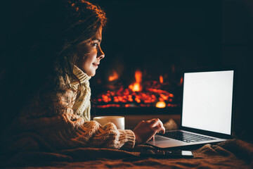 Woman doing online Christmas shopping near fireplace.