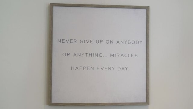 "Never give up on anybody or anything. Miracles happen every day". Motivational quote hanging in a frame on the wall