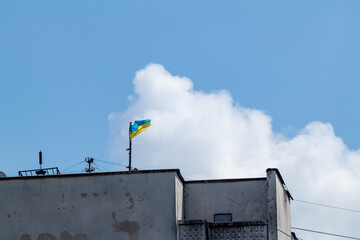 Ukrainian national flag on stock waving in wind on roof of high soviet architecture multistory...