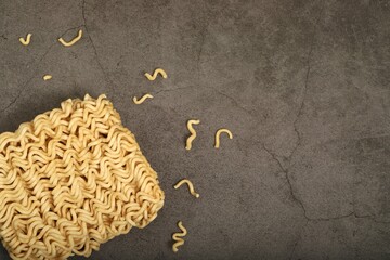 raw and broken instant noodles laid on gray background