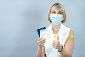 Tourist women ready for safe summer vacation. Studio portrait holding suitcase Wearing a mask raising arm vaccination record card after getting vaccinated with COVID-19 Coronavirus vaccination concept