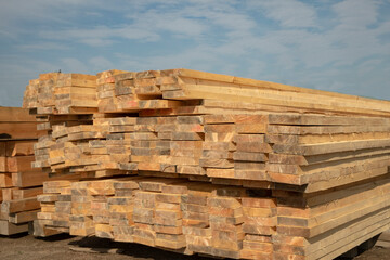 Outdoor lumber warehouse. A stack of 50mm dry board against a blue sky