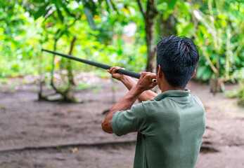 Ecuadorian indigenous Kichwa man doing a blowgun demonstration, traditional hunting method in the...