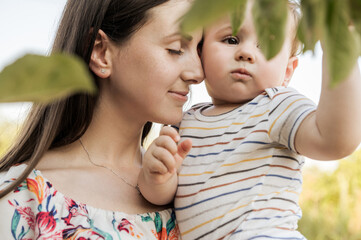 Closeup portrait of beautiful mother hold and hug her baby son with love and care at nature