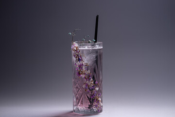 luxury violet fizz cocktail drink with flower decoration on grey background