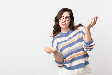 pretty woman shrugging with a dumb, crazy, confused, puzzled expression, feeling annoyed and...