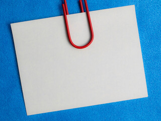 white blank note pinned to a blue notice board with a paper clip.
