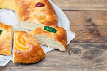 Christmas dessert, Roscón de Reyes cut on a wooden table. Copy space.