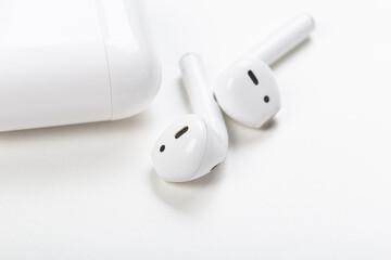 Modern wireless bluetooth earphones with charging case on a light gray background. The concept of...