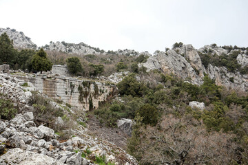 tall and massive stone wall of upper city of ancient Termessos in Turkey