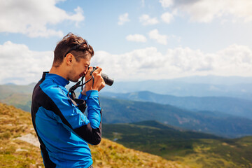 Obraz premium Photographer taking pictures of Carpathian mountains landscape. Man using camera to make photos and footage