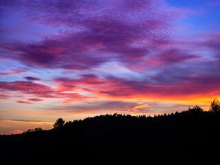 A purple haze inspired sunset with pink, purple and orange clouds over a forest mountain