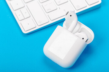 wireless bluetooth earphones with charging case on a blue background. The concept of modern...