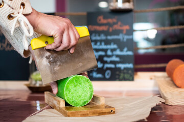 Hands of white European woman cutting organic handmade soap in small business zero waste retail by weight, close up view
