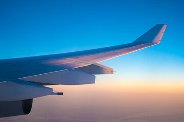 Naklejka na ściany i meble Airplane wing during flight at sunset