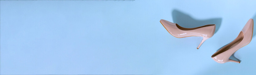 Classic beige women's shoes with medium heels on a blue background. The concept of sales and advertising. flatly. From above.
