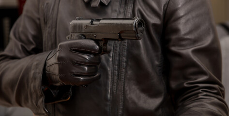 Fototapeta premium Gloved hand holding a pistol aiming, closeup view
