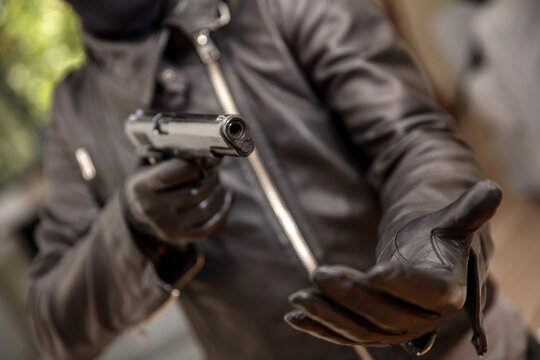 Thief gloved hand holding a pistol aiming, closeup view. Armed robbery concept