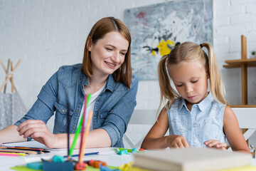 happy kindergarten teacher looking at preschooler kid