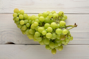 One bunch of ripe seedless grapes on a wooden table, close-up, top view.
