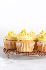 Group of vanilla cupcakes with yellow frosting on a cooling rack
