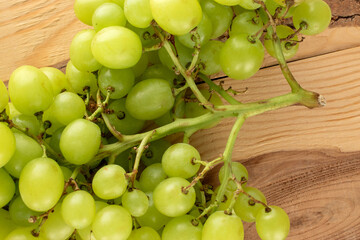 One bunch of ripe seedless grapes on a wooden table, close-up, top view.
