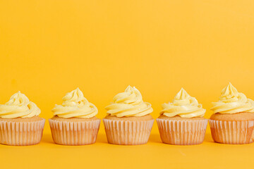 Vanilla cupcakes with yellow frosting on a bright yellow background