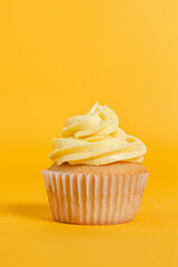 Vanilla cupcake with yellow frosting on a bright yellow background