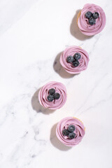 Obraz na płótnie Canvas Homemade vanilla cupcakes with blueberry buttercream and fresh blueberries on top on a white marble background