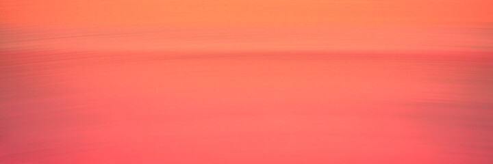 Peach-colored abstract wide seascape background. Warm sky and ocean with empty gradient motion blur backdrop. Cross-processed image of the tranquil twilight sea at Hyannis Harbor in Massachusetts.