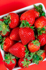 Fresh strawberries on a bright red background