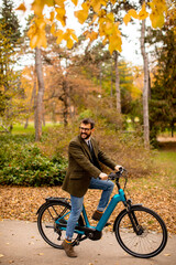 Young man with electric bicycle in the autumn park