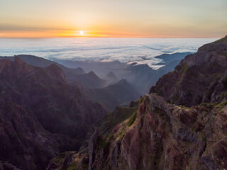 Spectacular landscape view of sunrise rising above sea of clouds surrounded with volcanic mountains.