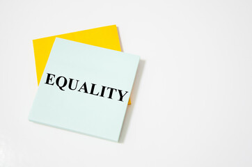 equality text written on a white notepad with colored pencils and a yellow background. word
