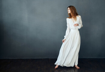 woman barefoot in a white dress dancing on a dark background