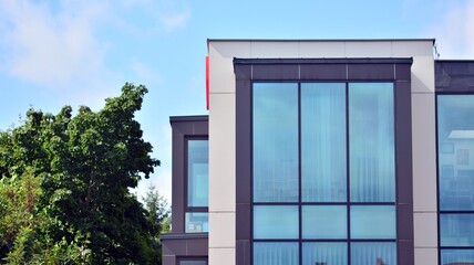 Modern building with windows and grey walls. Windows are reflecting light.