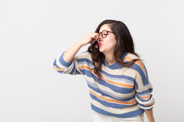 pretty woman feeling disgusted, holding nose to avoid smelling a foul and unpleasant stench