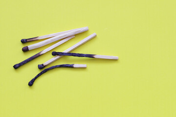 a bunch of burnt matches on a yellow background. copy location
