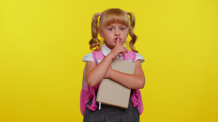 Shh be quiet please. Funny little pupil girl teenage student presses index finger to lips makes silence gesture sign do not tells secret on yellow studio background. Education, back to school, study