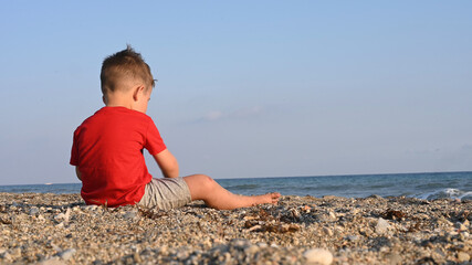 Fototapeta na wymiar Lonely child, playing alone, by the sea