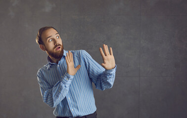 Oh no, please stop. Funny scared young man isolated on grey background doing protective hand gesture afraid of terrible danger, life troubles, work problems or vaccine injection jab shot. Fear concept - obrazy, fototapety, plakaty
