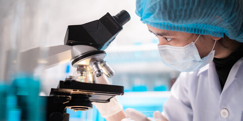 scientist looking through scientific microscope lense in laboratory, scientist doing research in...