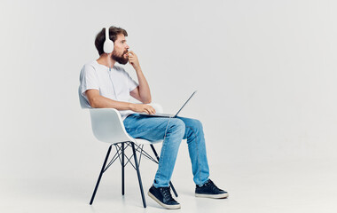 bearded man sitting on a chair with a laptop in headphones Lifestyle