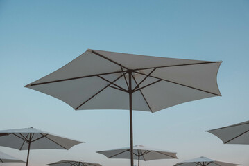 White beach umbrellas on sky background. Copy, empty space for text