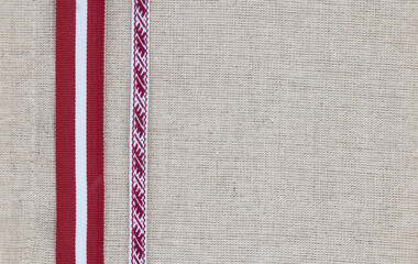 Composition of national latvian patterned ribbon and flag on linen fabric, banner