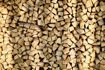 Heap of chopped firewood in pile close-up. Firewood storage close up. Stock of wooden logs. Chopped wood in bright sunlight. Rustic lifestyle. Woodpile with firewood full frame image. Wooden texture.