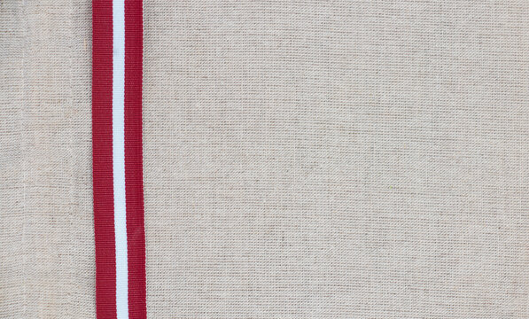 Composition of national latvian patterned ribbon flag on linen fabric